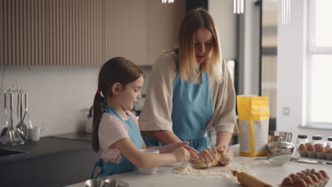 home-cooking-woman-and-little-girl-are-making-dough-for-bread-or-cake-in-kitchen-of-house-mother-is-kneading